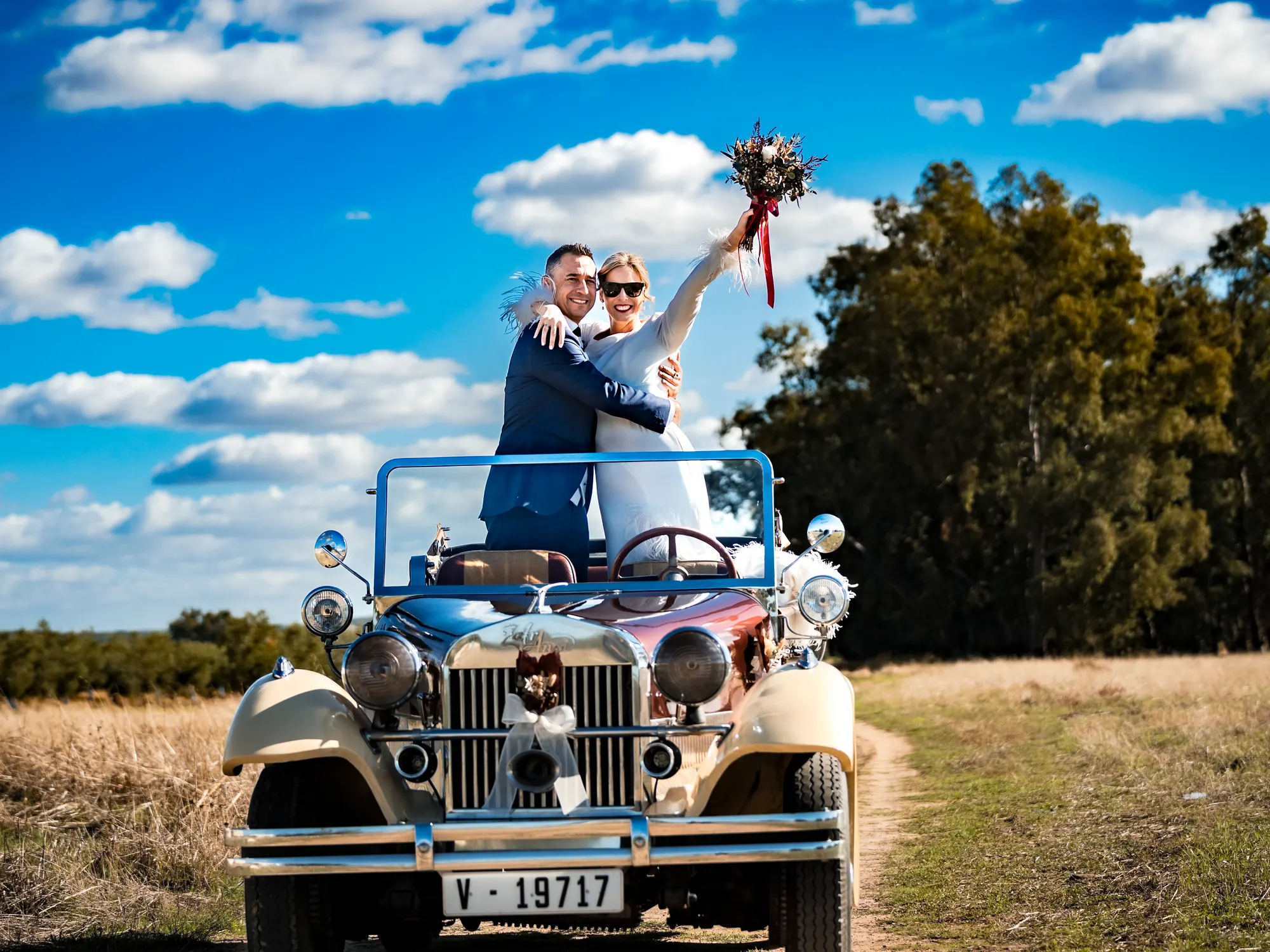 Novios celebrando subidos a un coche clásico descapotable