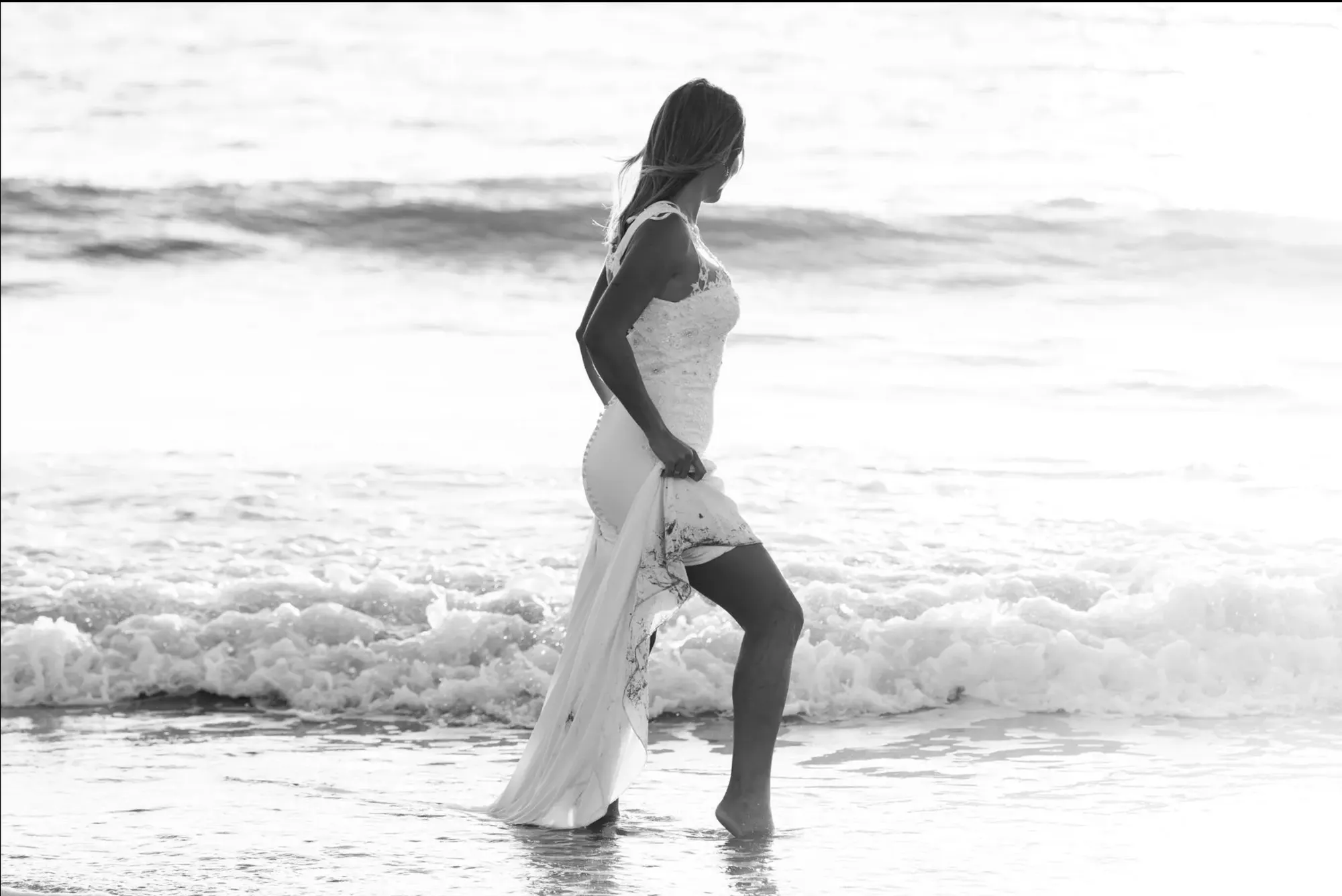 Novia caminando entre las olas, en blanco y negro