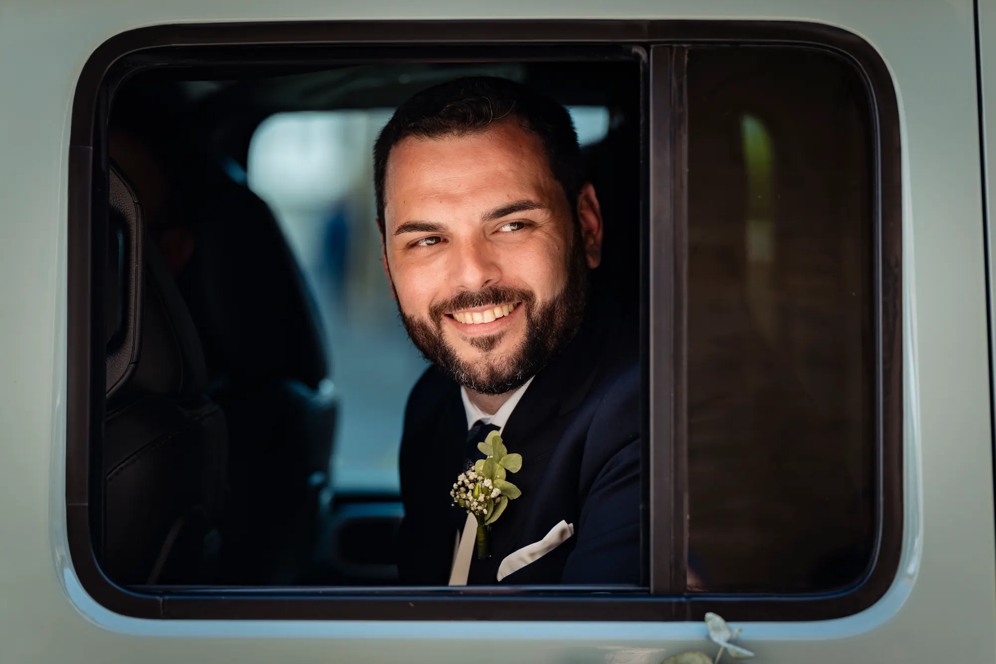 Novio sonriente asomado a la ventanilla del coche
