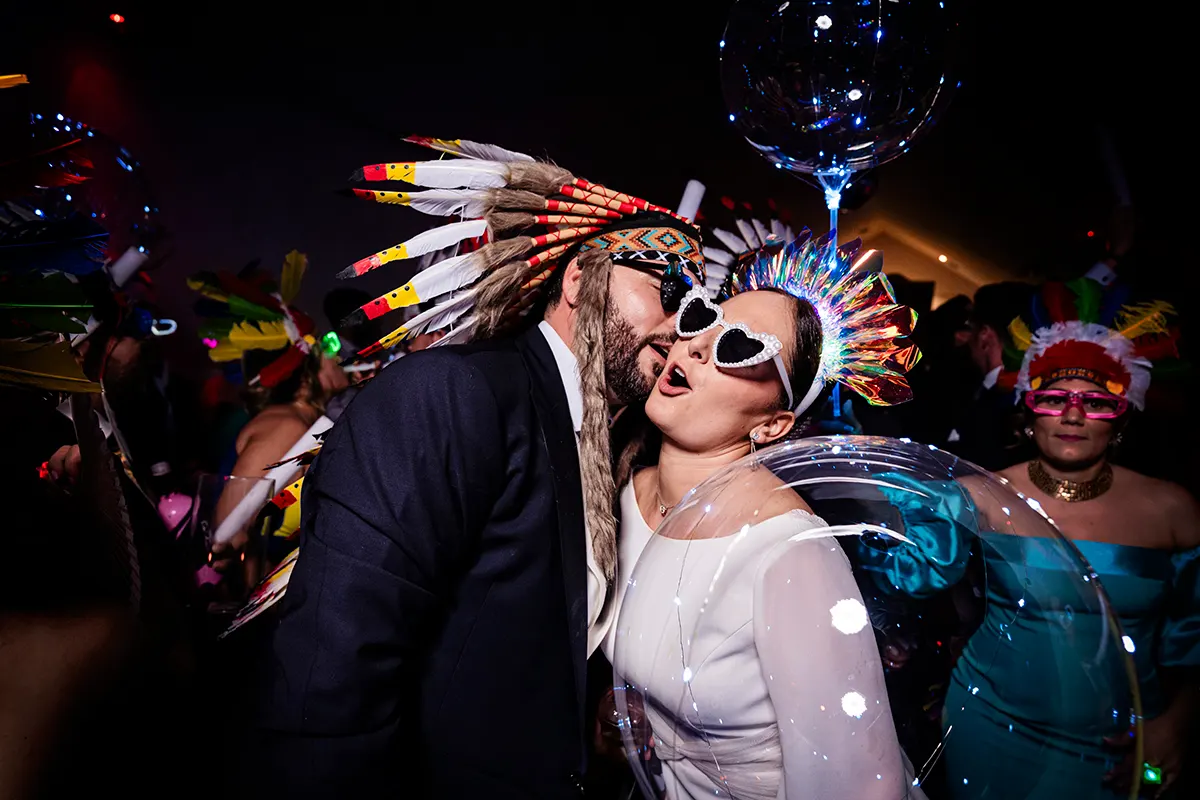 Novios con gafas y tocados de plumas en la fiesta