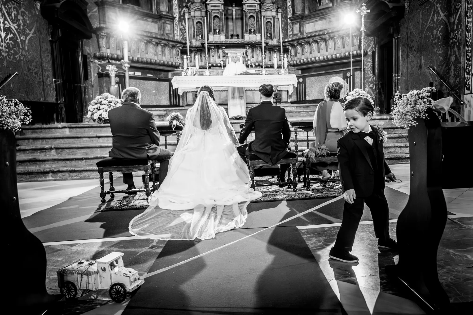 Ceremonia en la iglesia con un niño jugando con un coche de juguete