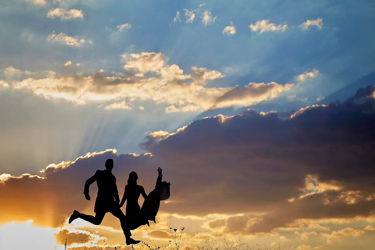 Silueta de los novios saltando bajo los rayos del sol