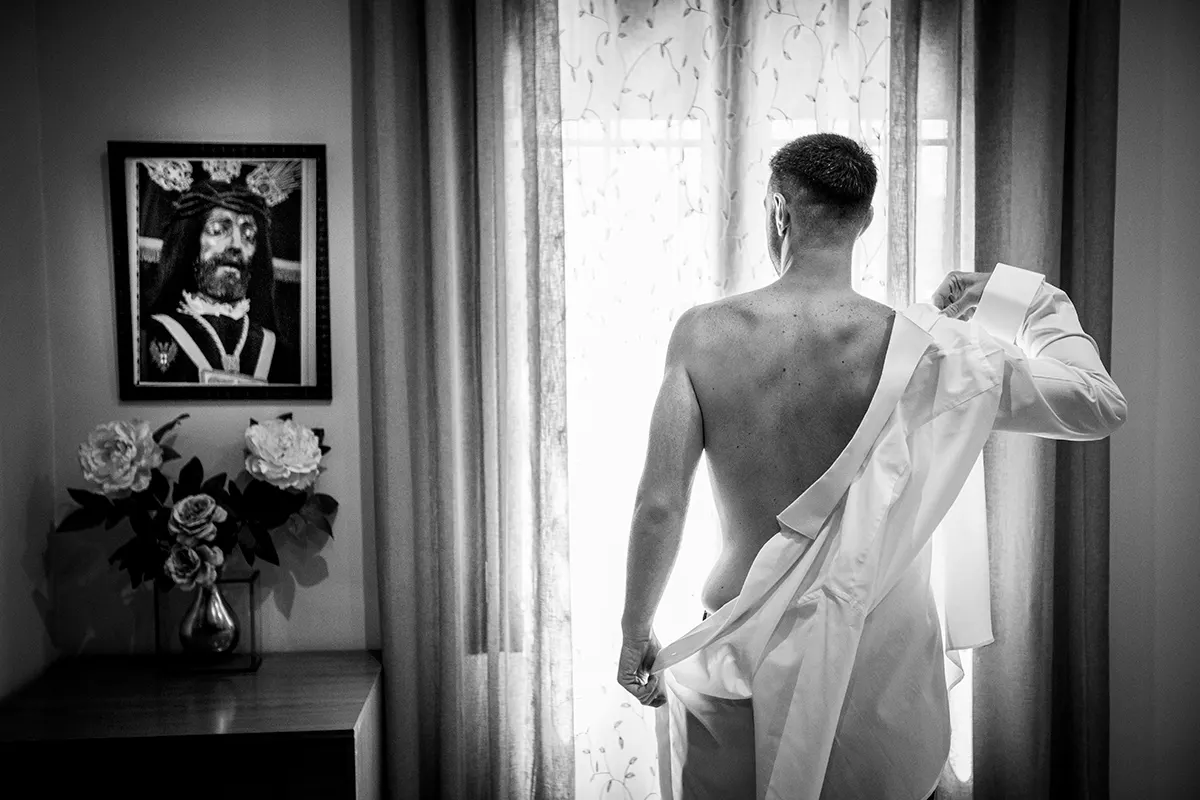 Novio vistiéndose junto a la ventana