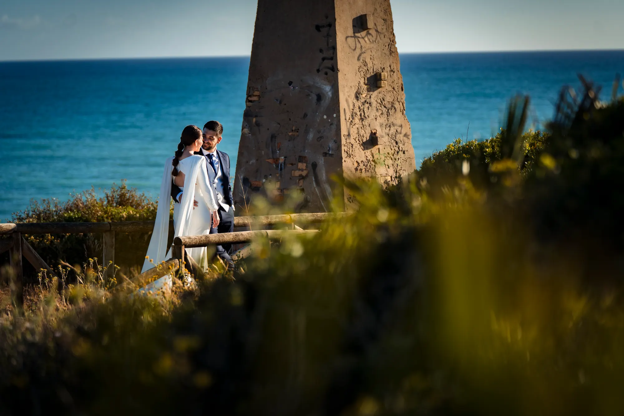 Novios junto a una torre almenara frente al mar