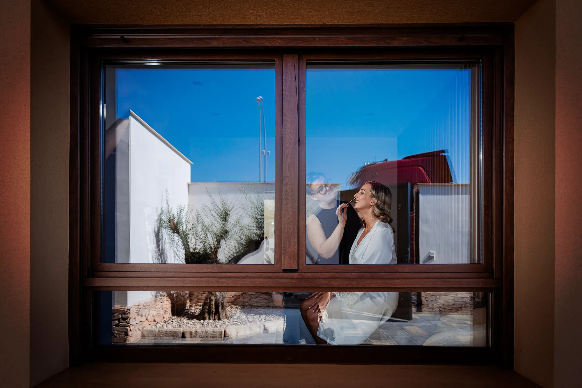 Novia reflejada en una ventana durante los preparativos