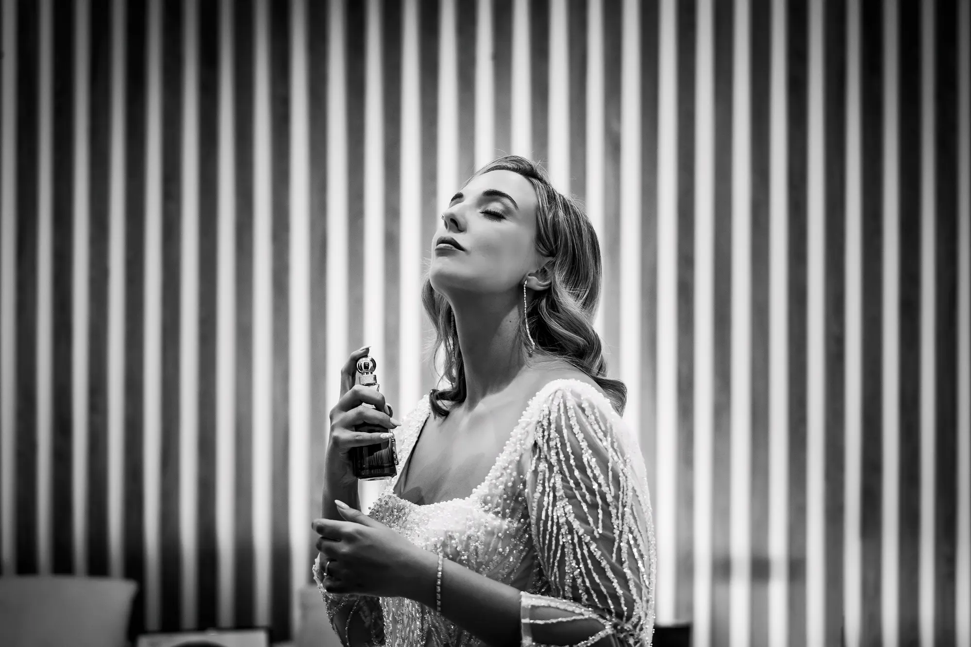 Novia perfumándose a contraluz, en blanco y negro
