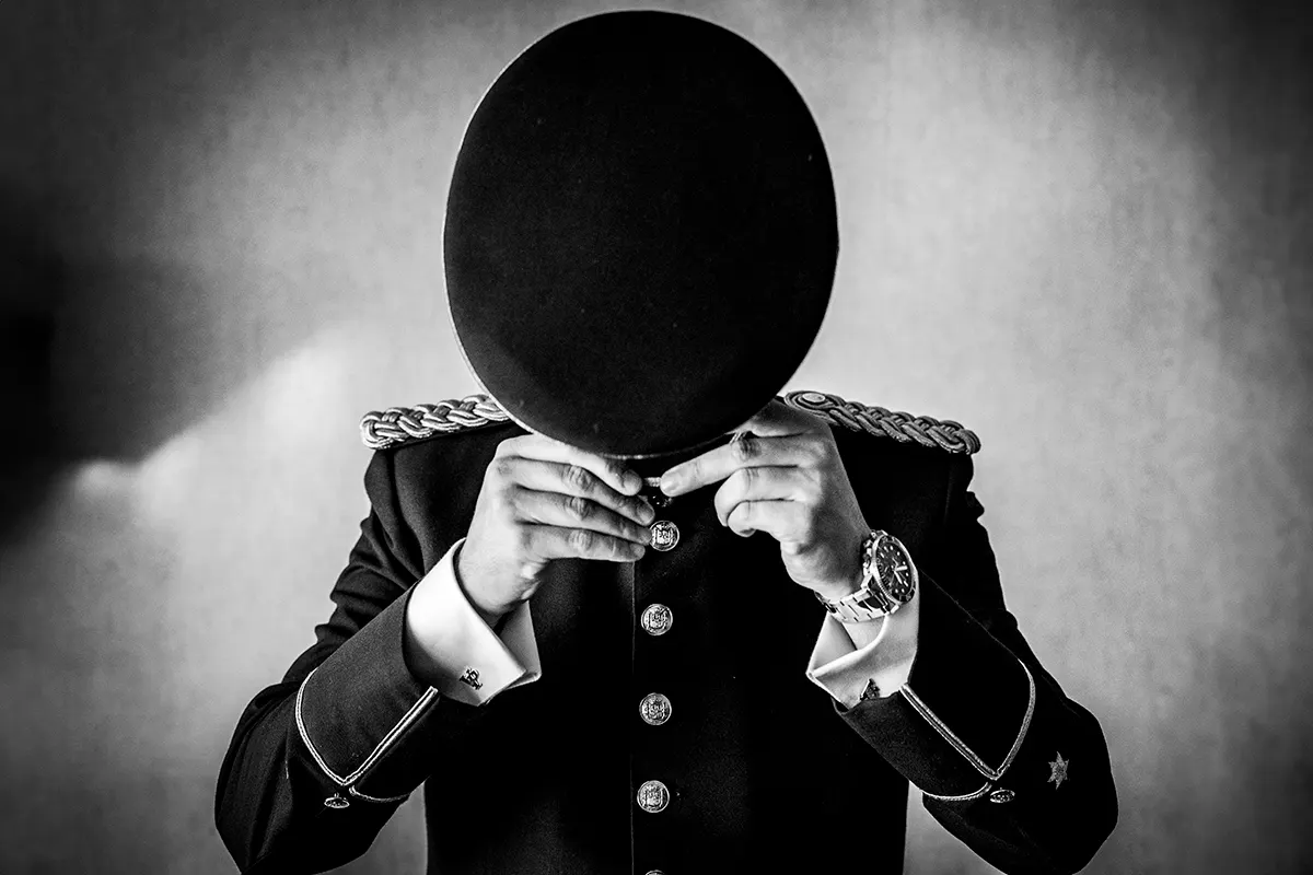 Novio con uniforme de gala tapándose la cara con un globo negro