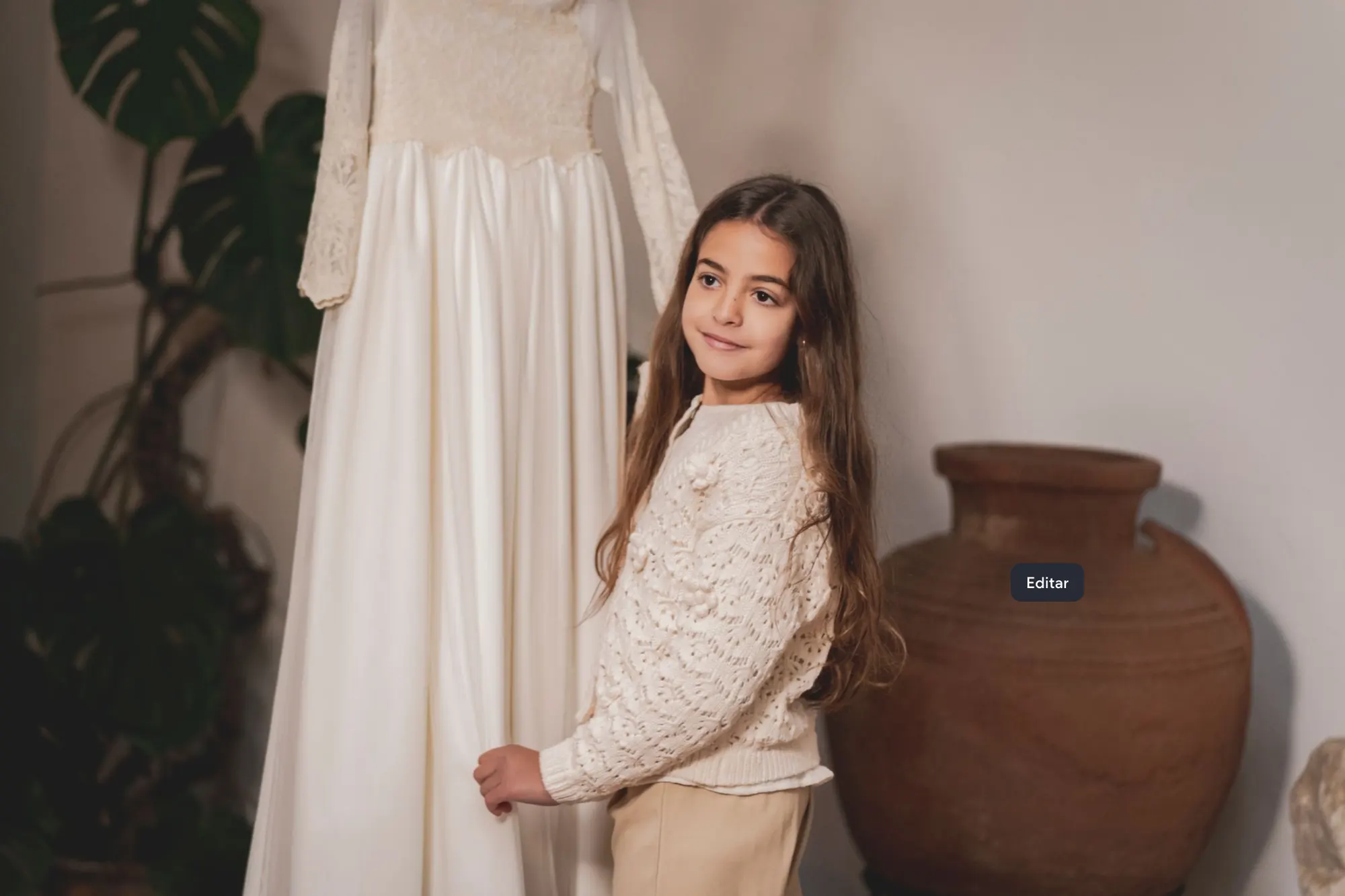 Niña junto a su vestido de comunión y una tinaja de barro