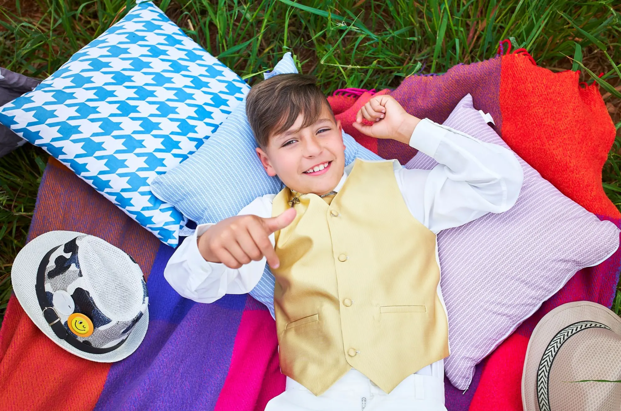 Niño de comunión tumbado sobre cojines de colores