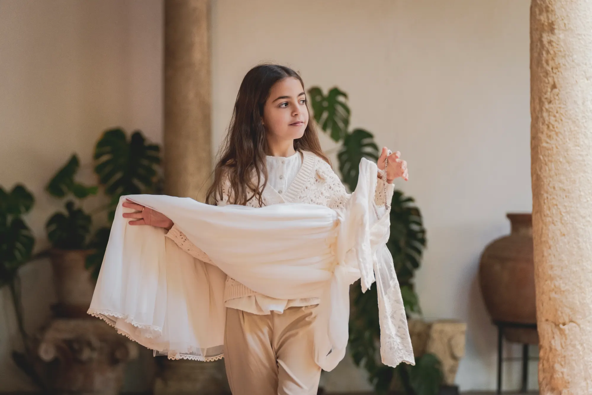 Niña de comunión jugando con su vestido en un patio