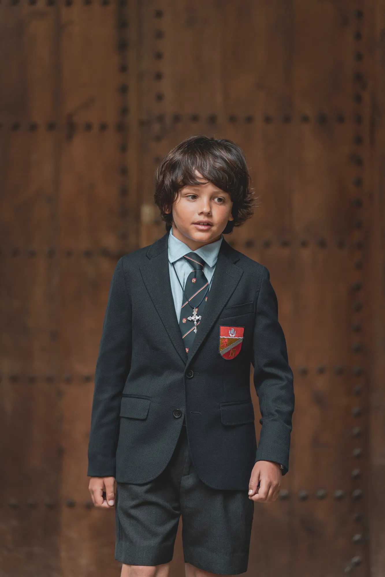 Niño de comunión con traje frente a un portón