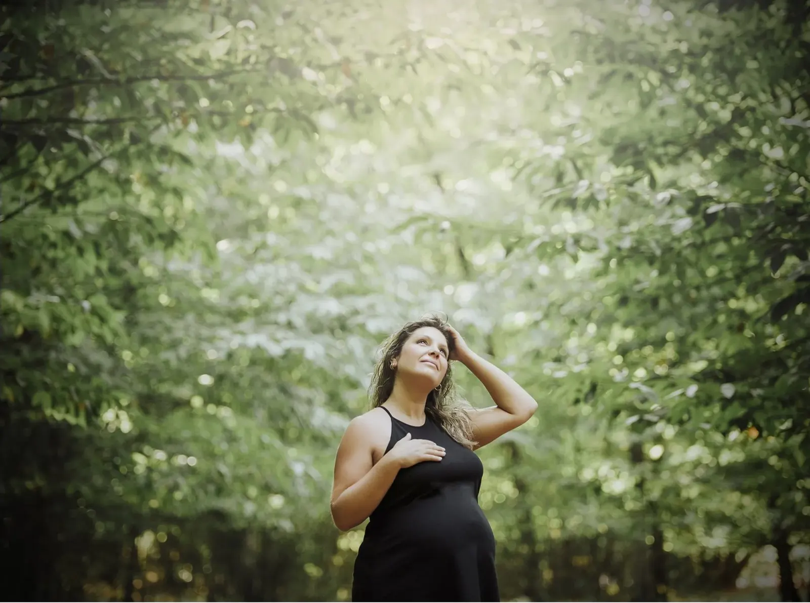 Embarazada con vestido negro en un bosque